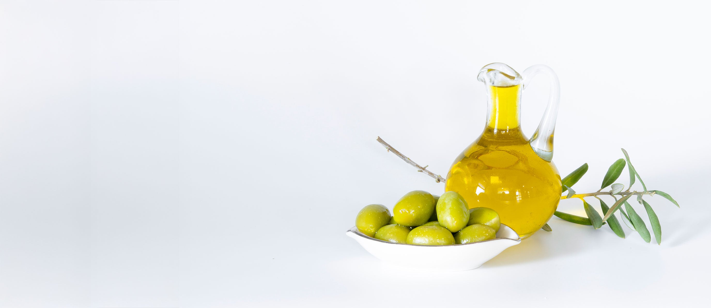 Olive oil bottle with green olives and olive branch on a white background