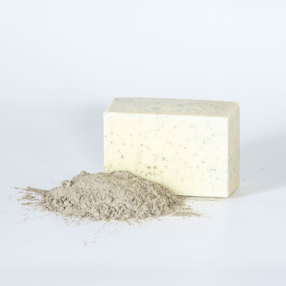 Bar of black sea salt soap on a textured surface with a purple background