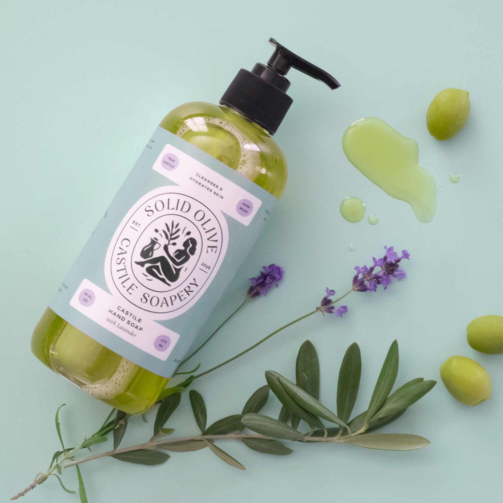 Bottle of Solid Olive & Castile Soapery hand soap with a pump on a textured surface and purple background