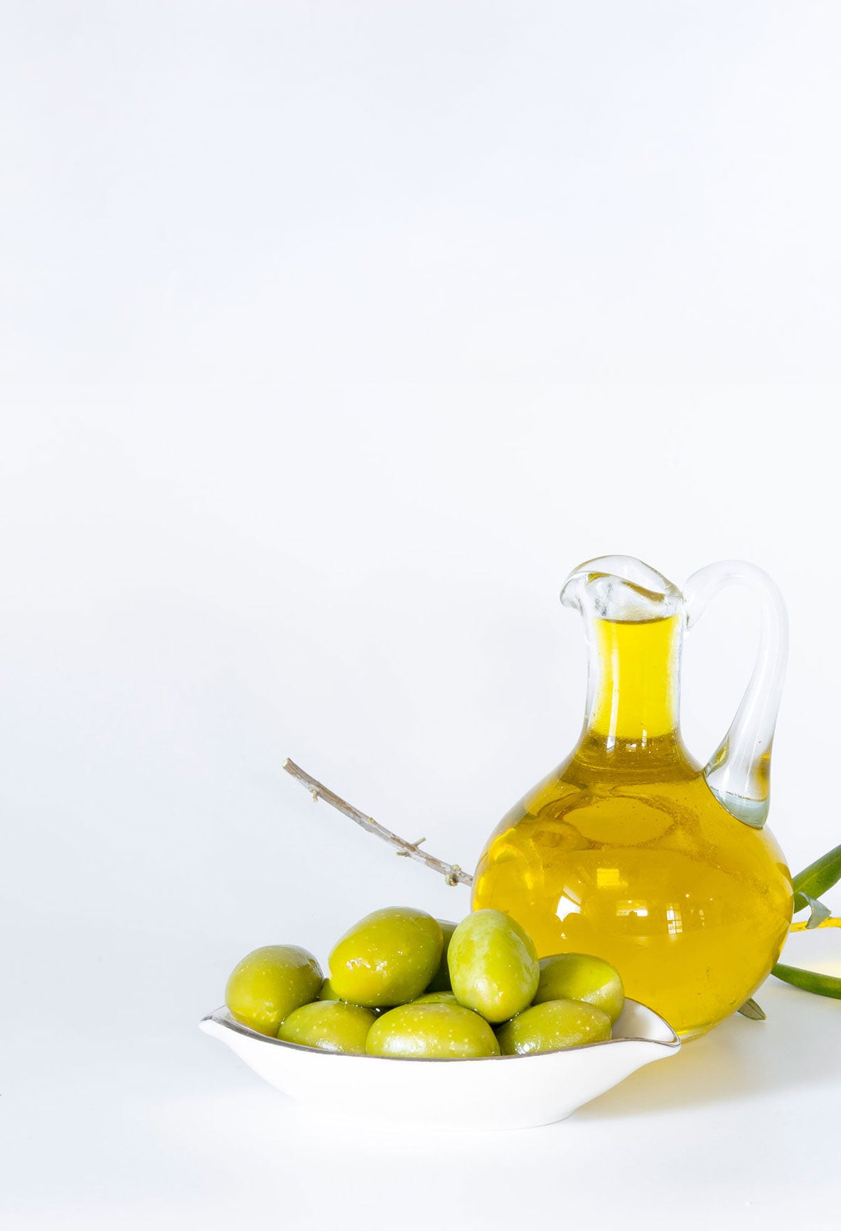 Olive oil bottle and olives on a white background