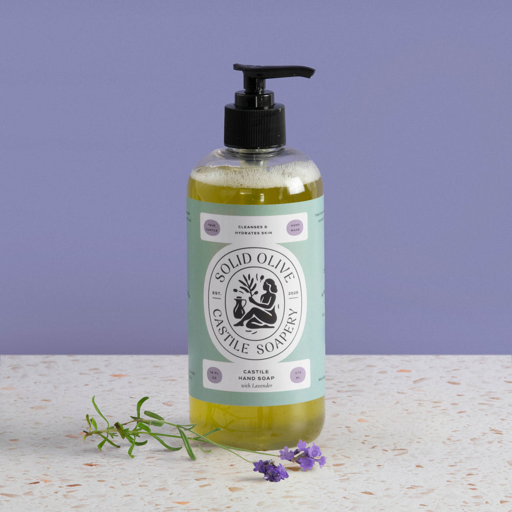 Bottle of Solid Olive & Castile Soapery hand soap with a pump on a textured surface and purple background