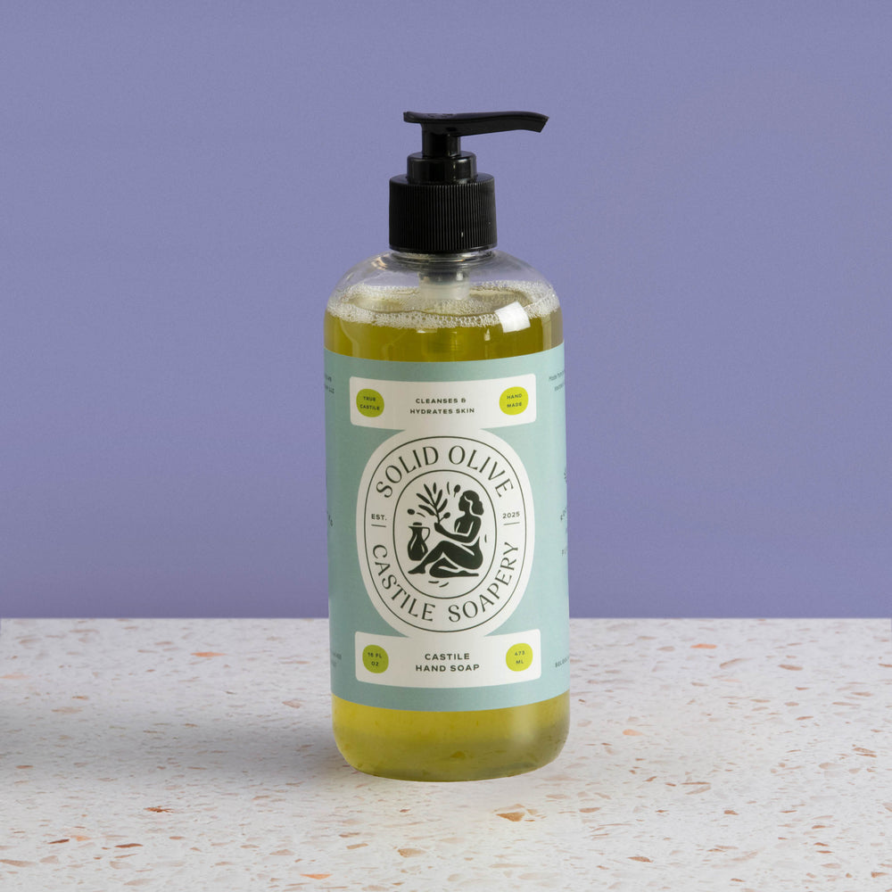 Bottle of Solid Olive Castile Soap on a textured surface with a purple background