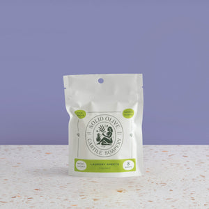 Solid Olive Laundry Sheets packaging on a textured surface with a purple background