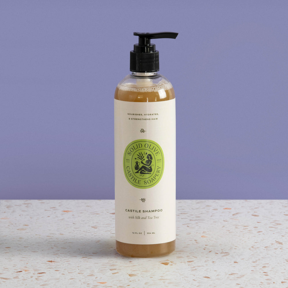 Bottle of castile shampoo with a green label on a light surface and purple background