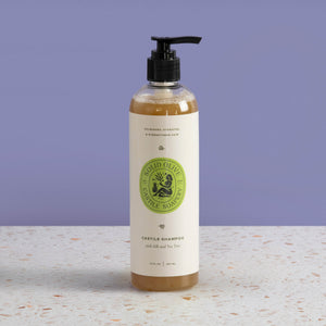 Bottle of castile shampoo with a green label on a light surface and purple background