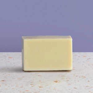 Bar of baby soap on a textured surface with a purple background