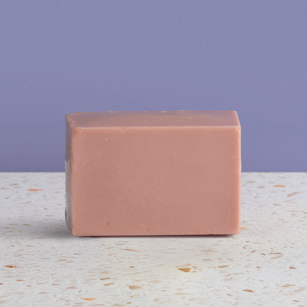 Bar of soap on a textured surface with a purple background