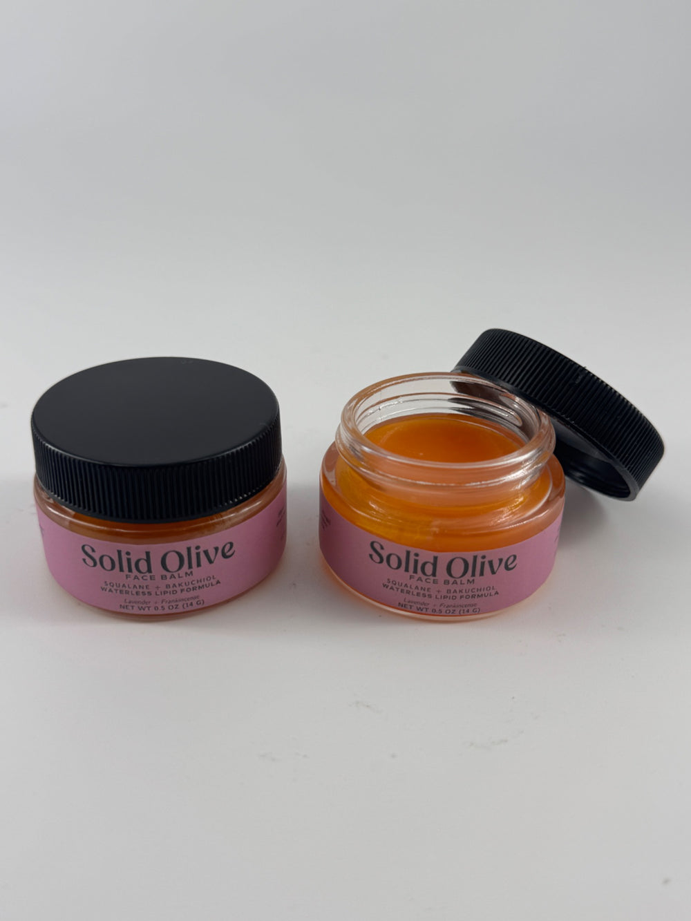 Solid Olive 0.5 oz Face Balm in glass jars, with one jar open