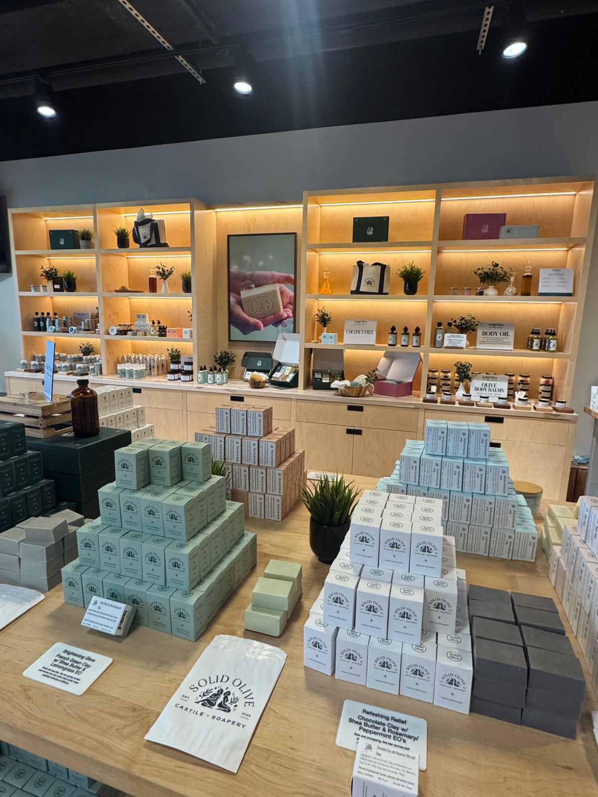 Inside The Solid Olive Soap Company in Highlands Ranch, with illuminated wood cabinets and displays of handcrafted soaps.
