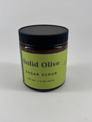 Solid Olive 3.5 oz sugar scrub in an amber glass jar with black lid