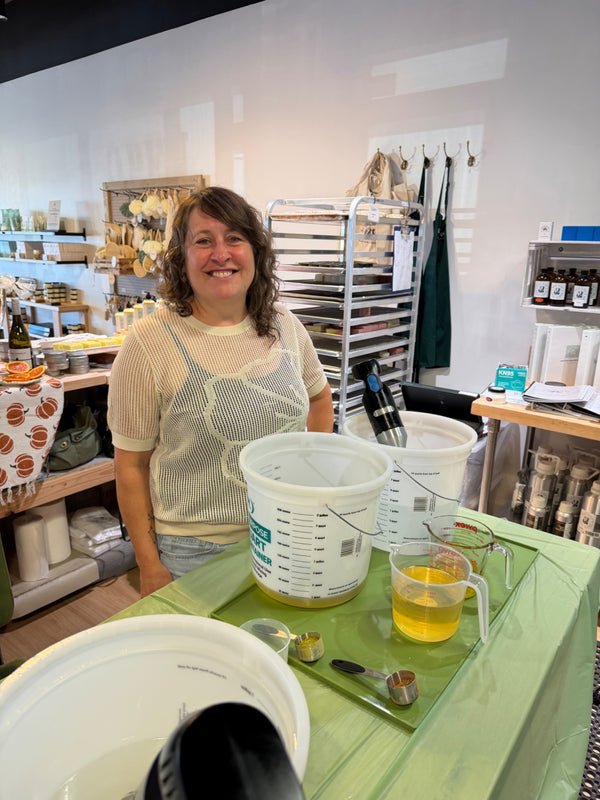 Workshop attendee at a soapmaking station with oils and equipment